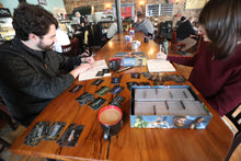Load image into Gallery viewer, a young man and woman sit in a cafe, using Reckless Deck PSYCHE for brainstorming and idea generating
